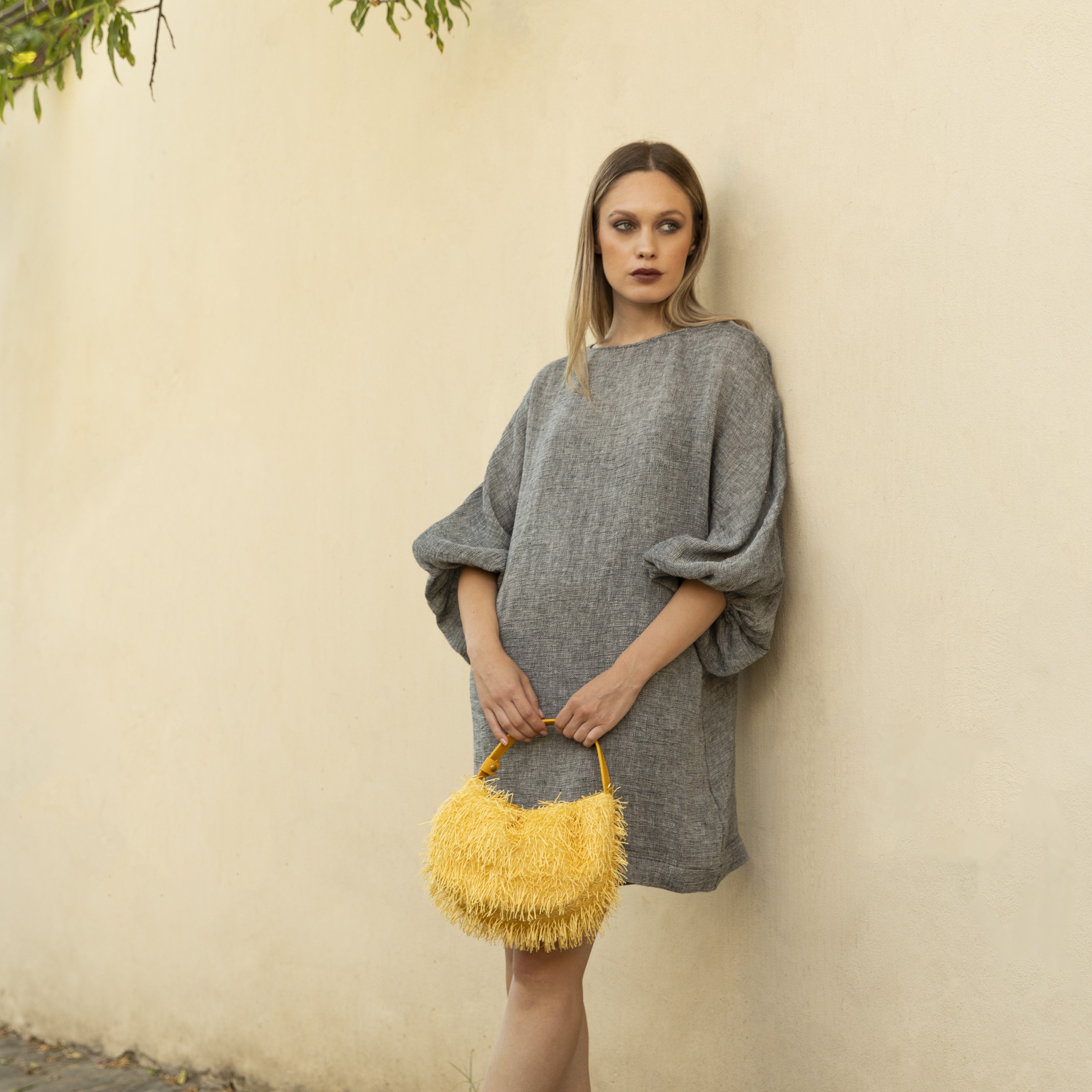 borsa da occasione, da festa, da sera con frange luminosa color giallo limone brand Arron indossata a mano