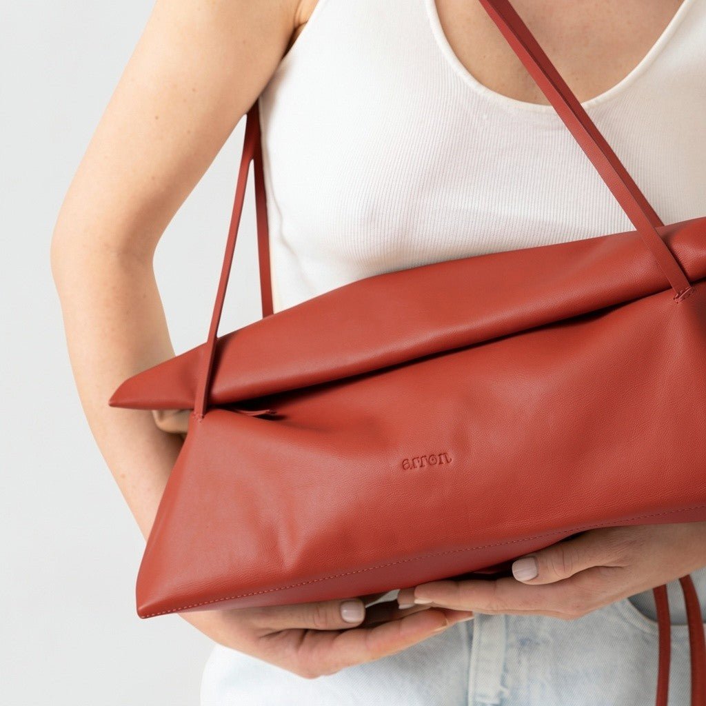 borsa Otta made in Italy del brand Arron in pelle color mattone, forma allungata east west, trendy, leggera manici fini, indossata